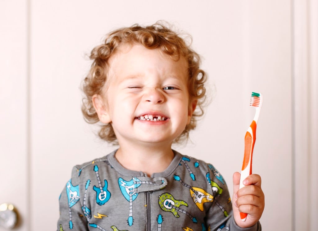 Рыжий мальчик с молочными зубами и зубной щеткой