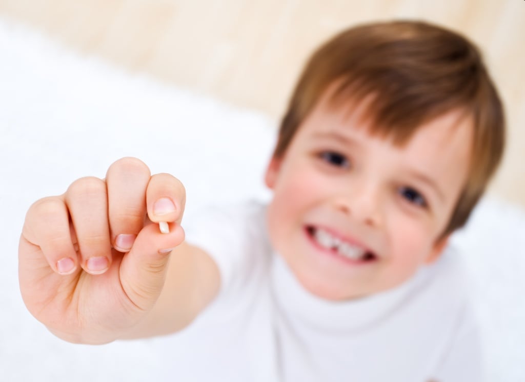 Мальчик с молочным зубом в руках